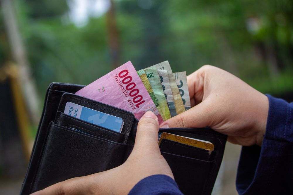 Tangan menghitung uang rupiah dari dompet