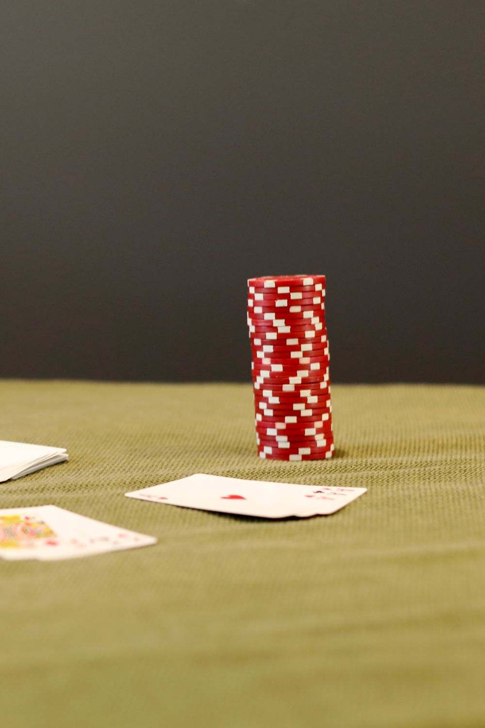 Keripik poker merah dan kartu remi di atas meja kain hijau